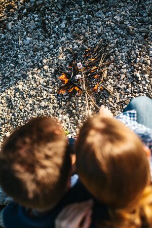 People or a couple prepare or roast marshmallows on a campfire in nature.の写真素材
