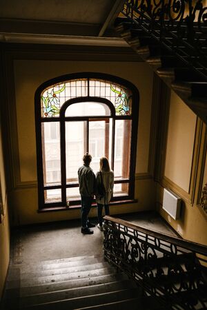 A couple is standing and looking out the window and dreaming or spending time together.の写真素材
