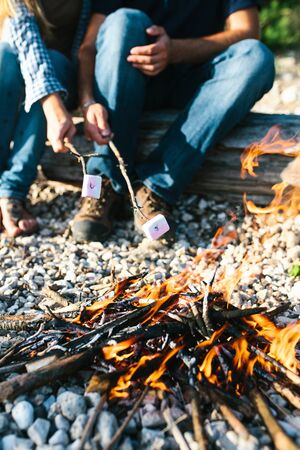 People or a couple prepare or roast marshmallows on a campfire in nature.の写真素材