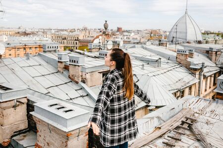 A girl on the roof of a house in solitude meditates or enjoys life or a digital detox. The search for the soul.の写真素材