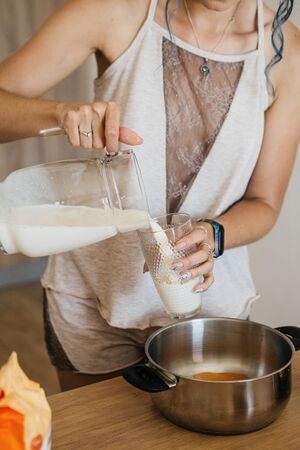 A girl pours milk into a glass to drink or to prepare a meal.の写真素材