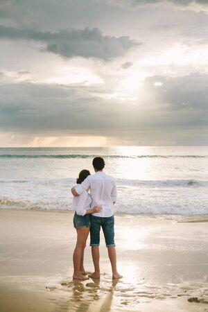 A man hugs a woman. They stand and look at the sea. Solitude together.の写真素材