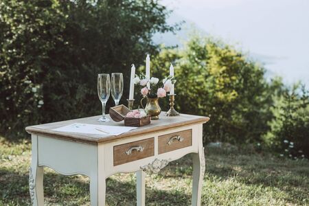 Table with wedding attributes including candles and a bridal bouquet. Wedding celebration in nature. Scenery and decoration.の写真素材