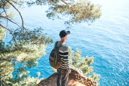 Tourist with a backpack near the sea. Travel alone. Looks into the distance.の写真素材