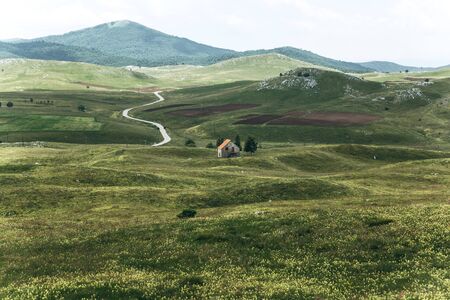 Beautiful view of the natural landscape in Montenegro with a field and authentic house with a mountain in the background.の写真素材