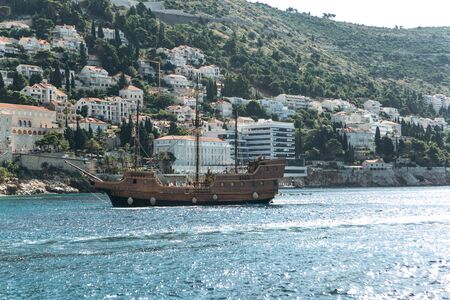 A ship is sailing against the background of old buildings in Dubrovnik in Croatia.の写真素材