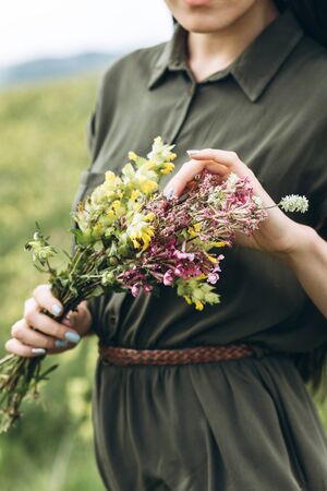 Close-up of a girl holding wildflowers in her hands.の写真素材