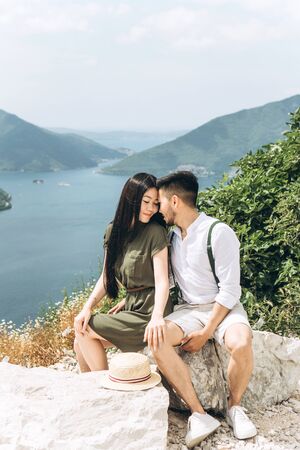 Young beautiful couple sits together on the background of the sea and mountains in Montenegro.の写真素材