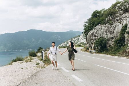A young couple running along the road holding hands. They are happy together.の写真素材