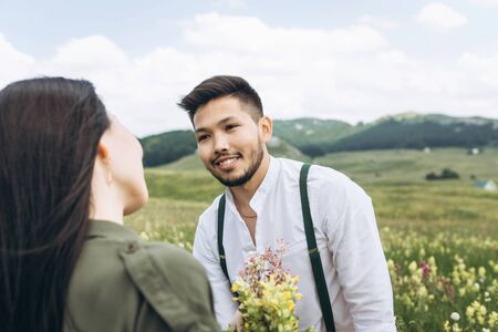 Portrait of a handsome positive man who gave his woman wildflowers. Relationships and love.