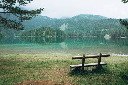 A wooden bench overlooking a lake called Black Lake and a forest in Montenegro.の写真素材