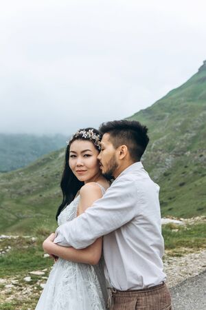 Portrait of a bride hugged by her bridegroom. Outdoor wedding.の写真素材