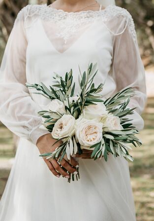 The bride holds in her hands a beautiful wedding bouquet of white roses.の写真素材