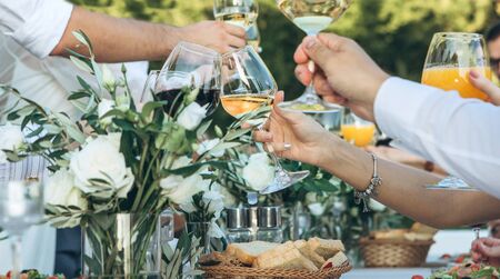 People hold wine glasses in their hands and clink glasses. Celebrating an event, birthday or wedding, or maybe another.の写真素材