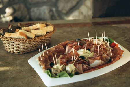 Plate with various meat snacks and cheese. In the background is a plate of bread.の写真素材
