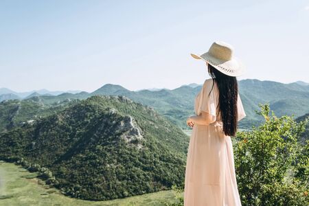 Beautiful elegant woman in a hat admires a beautiful view of the natural landscape in Montenegroの写真素材