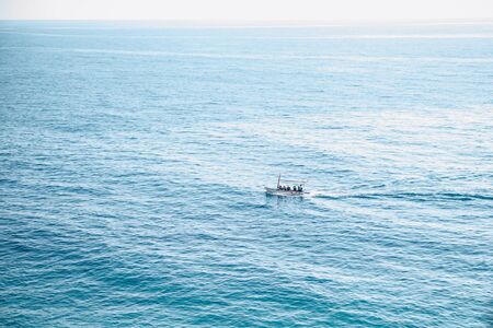 A motor boat with unrecognizable people floats in the sea in a minimal style.の写真素材