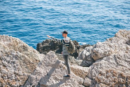 Tourist with a backpack near the sea. He shows with his hand the direction.の写真素材