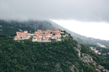 View of traditional residential buildings in the mountains of Montenegro in cloudy and rainy weather. Fog or haze above the mountains.の写真素材
