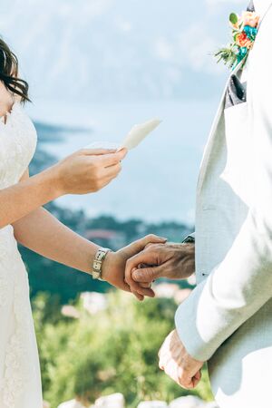 The bride reads her oath to the groom and they hold hands.の写真素材