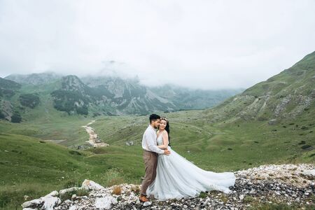 Groom with a bride or couple on a background of a beautiful mountain landscape. Wedding in the highlands.の写真素材