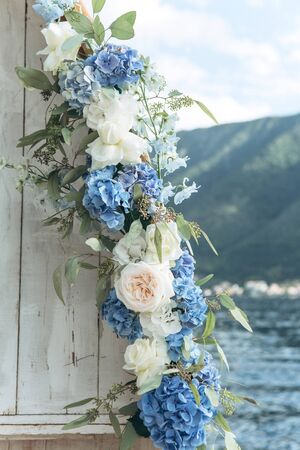 Close-up decoration of fresh blue hydrangeas and white peony roses at a wedding or other event. Decoration with flowers.の写真素材