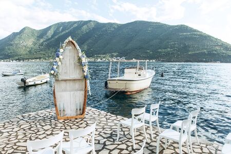 A wooden boat decorated with flowers as a wedding arch on the background of the sea. Preparing for the wedding.の写真素材