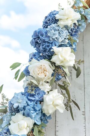Close-up decoration of fresh blue hydrangeas and white peony roses at a wedding or other event. Decoration with flowers.の写真素材