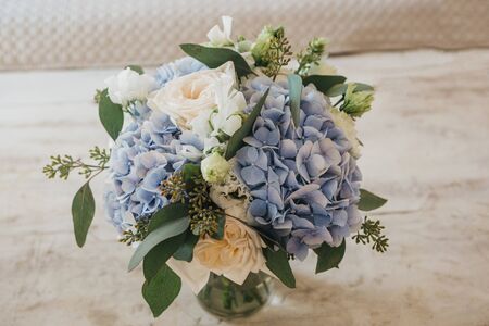 Close-up of a bouquet of flowers - blue Garden Hydrangeas and white Peony Roses in a vase on the table.の写真素材