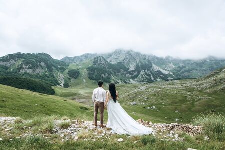 A couple in wedding dresses or the bride and groom together against the backdrop of a mountain landscape.の写真素材