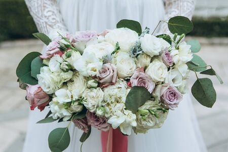 The bride holds in her hands a beautiful wedding bouquet of roses and other flowersの写真素材