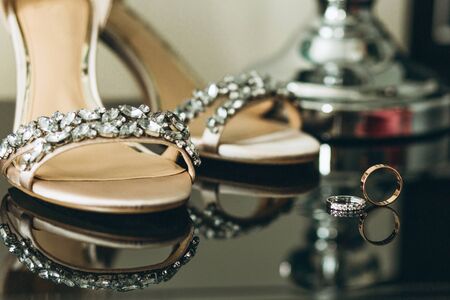 Beautiful wedding shoes and a pair of wedding rings nearby. Preparing for the wedding. Selective focusの写真素材