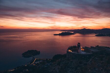Silhouettes of the bride and groom admire the beautiful sunset and natural landscape in Montenegro.の写真素材