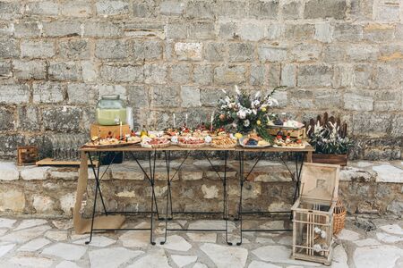 Catering or food service outside the home. Tables with food decorated in rustic style. Preparing for the celebration.の写真素材