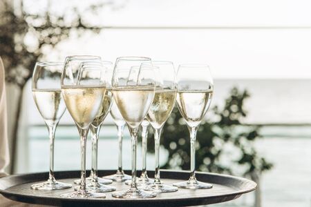 Glasses with champagne or white sparkling wine on a tray in a row.の写真素材