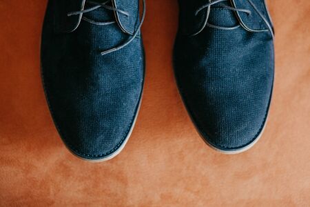 Closeup of dark blue nubuck new shoes on a coral or orange colored surface.の写真素材