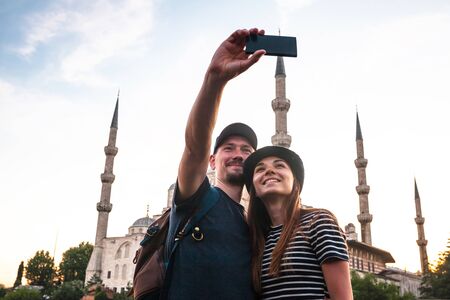 A couple of tourists taking a selfie against the backdrop of the Blue Mosque in Istanbul. Visiting Turkey and its attractions.の写真素材