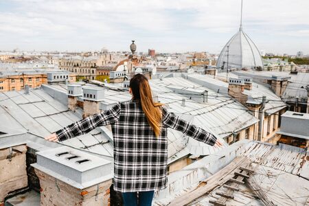 A girl on the roof of a house in solitude meditates or enjoys life or a digital detox. The search for the soul.の写真素材