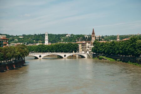 Beautiful view of traditional architecture, a cathedral or church and a bridge over a river in Verona in Italy.の写真素材