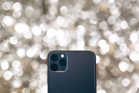 Modern phone with a triple camera on a silver background.の写真素材