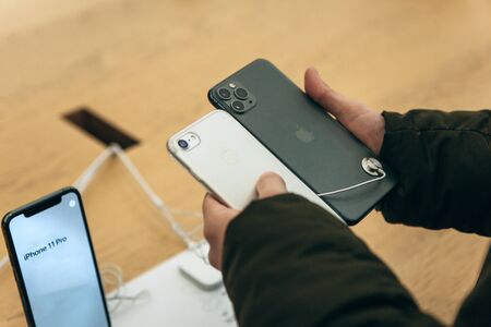 Turkey, Istanbul, December 17, 2019: The buyer compares the camera on the old iPhone and the latest modern iPhone 11 in the Apple storeのeditorial素材