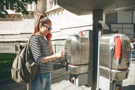 Girl tourist or student with a backpack talking or calling on a street phone on a street in Italy. Tourism and communications.の写真素材