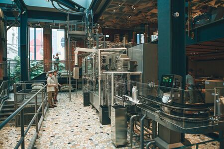 Italy, Milan, May 30, 2019: Conveyor for packing coffee beans at Starbucks Reserve in Milan. The technological process with employees.のeditorial素材