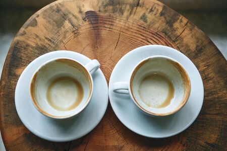 Two empty cups after drinking coffee on a wooden table. Concept for ending a meeting or something...