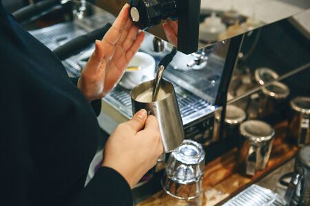 Close-up of a barista preparing milk in a coffee machine for adding to coffee.の写真素材
