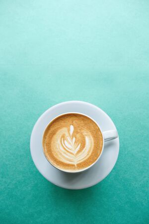 Close up of a cup of fresh cappuccino coffee on a mint background in minimal style.の写真素材