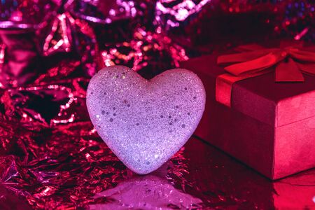 Heart and box with a gift on a trendy glowing red background. Valentine's day celebration or wedding concept or other love event.の写真素材
