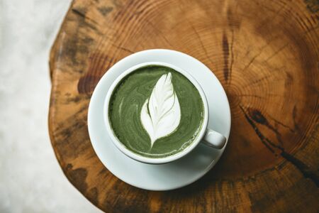 Fresh aromatic green matcha latte tea on a wooden table. Natural antioxidant and dietary product.の写真素材