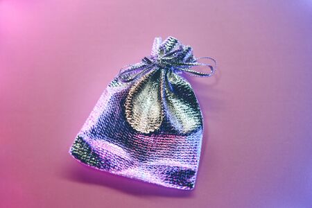 Silver small gift bag on a gradient background illuminated by neon light.