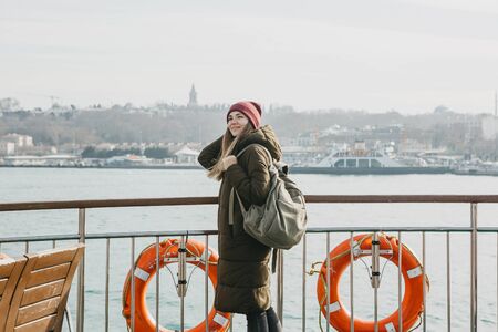 A student or tourist girl is standing on the deck or sailing on a ferry along the Bosphorus in...